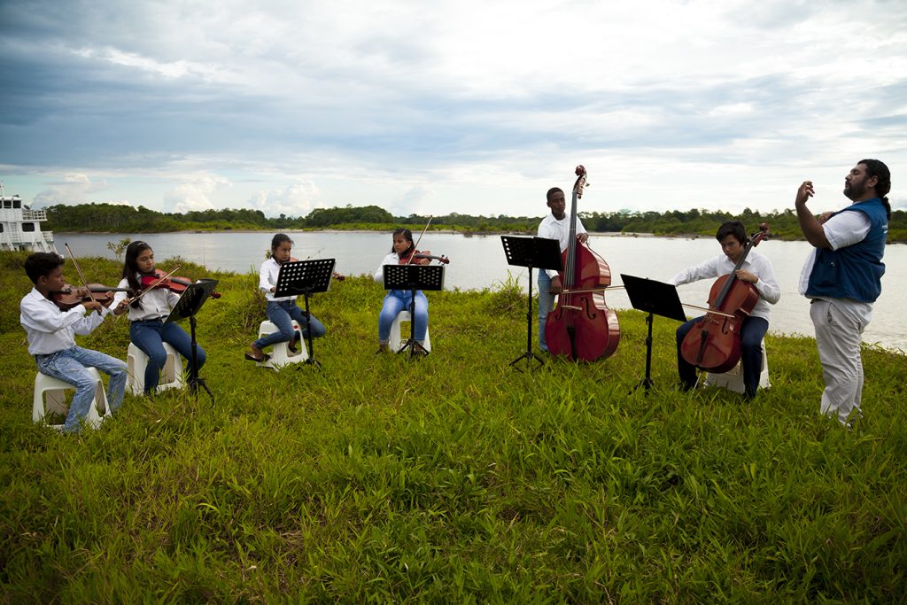 Niños, niñas y jóvenes del centro musical en Puerto Asís ensayando junto con Director de Batuta junto al río Putumayo