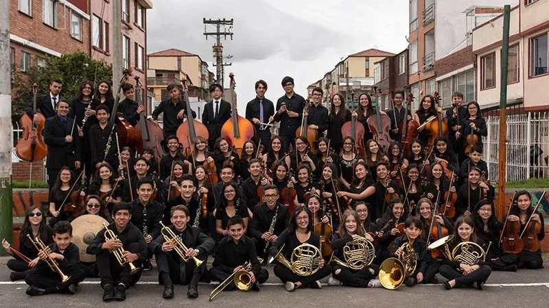 Integrantes la orquesta Batuta Bogotá con sus instrumentos en mano en una foto grupal en un parque