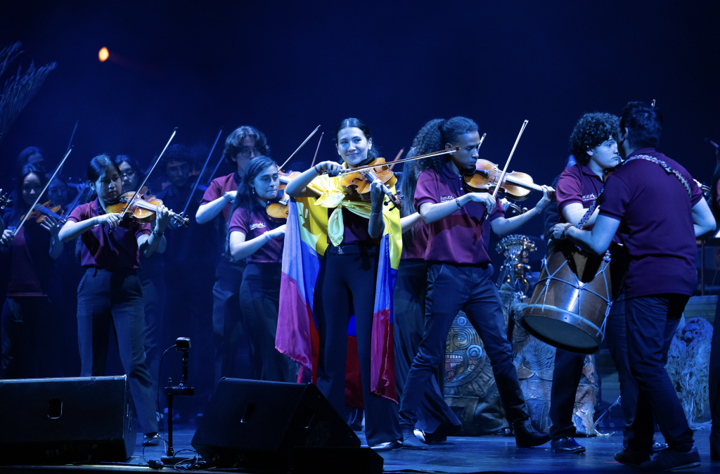 Integrantes de orquesta sinfónica juvenil tocan violines en concierto