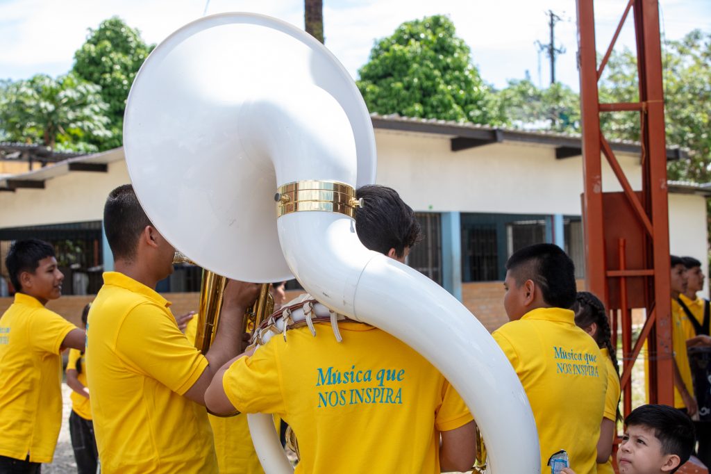 Un grupo de jóvenes con camisetas de "Música que nos inspira" de espaldas con instrumentos