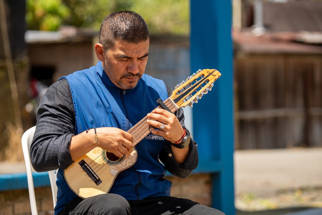 Profesor de Batuta y Ecopetrol sentado tocando un charango