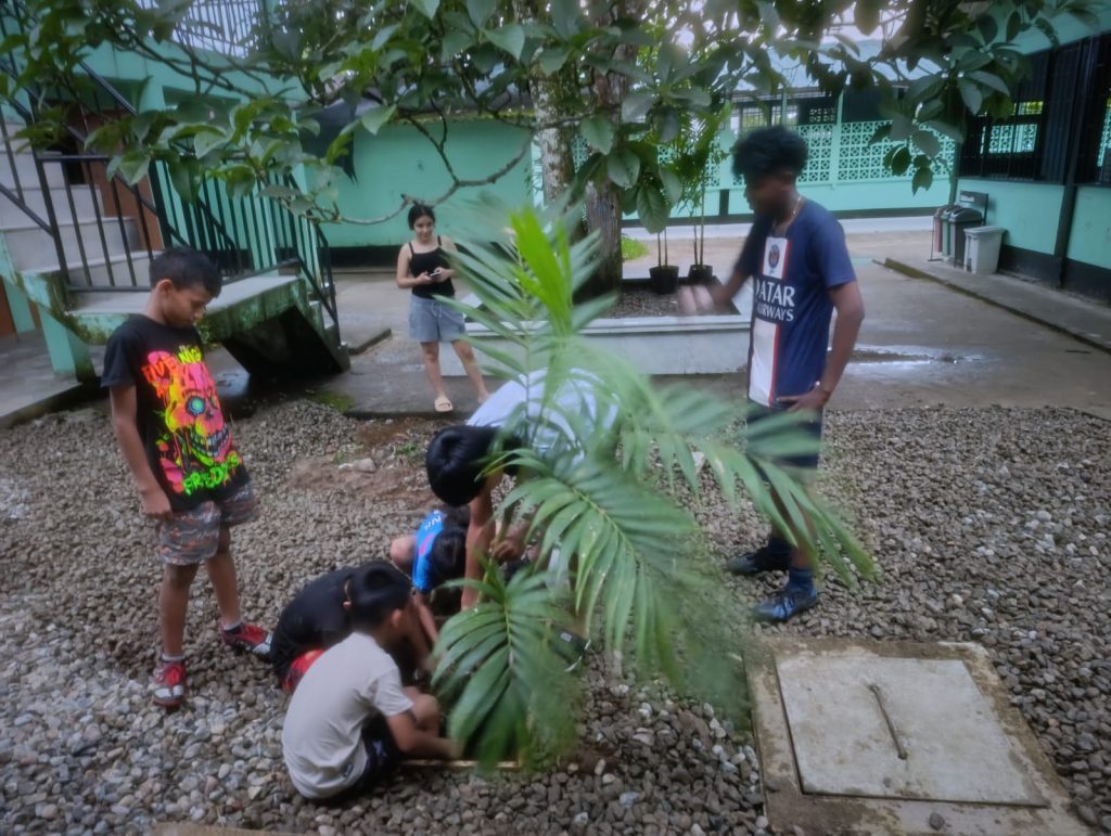 Profesor y estudiantes del centro musical las palmeras plantando una planta en su huerta