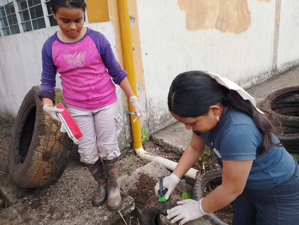 Dos niñas reutilizando una llanta para convertirla en una maceta para plantas