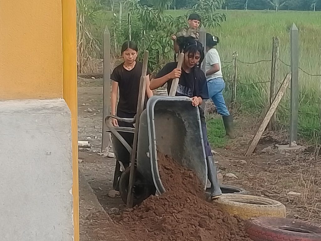 Joven echando tierra desde una carreta para preparar el suelo para la siembra.