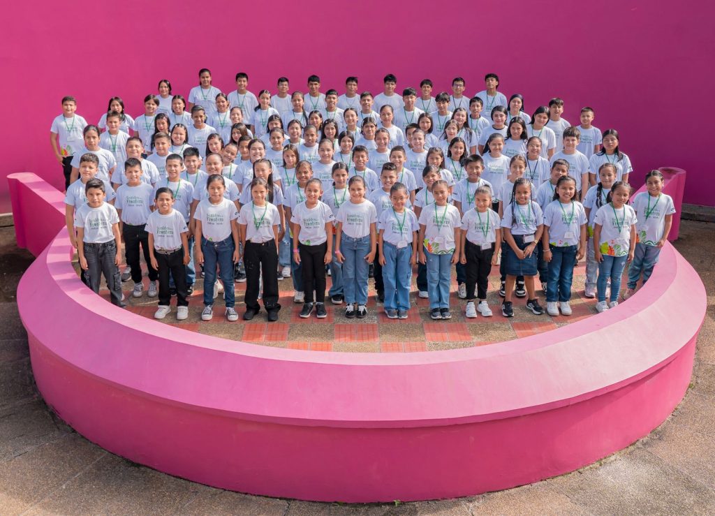 92 niños, niñas y jóvenes de Sonidos de la frontera en una tarima rosada