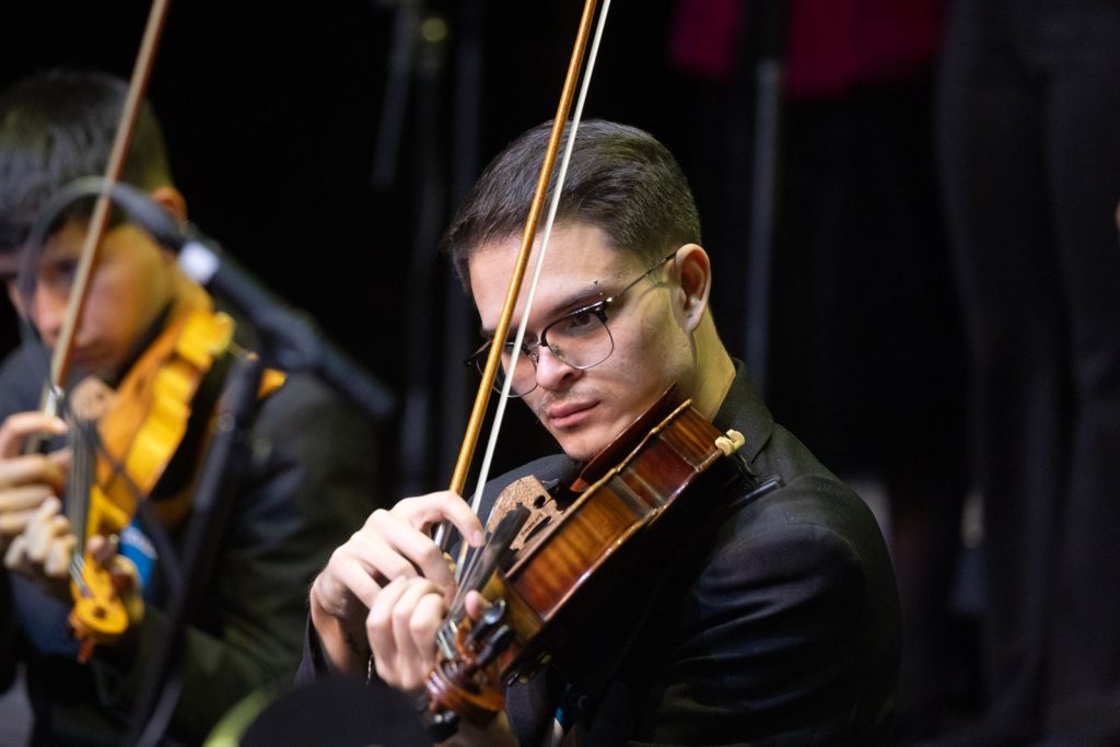 Jóven integrante de Batuta tocando el violín durante presentación musical