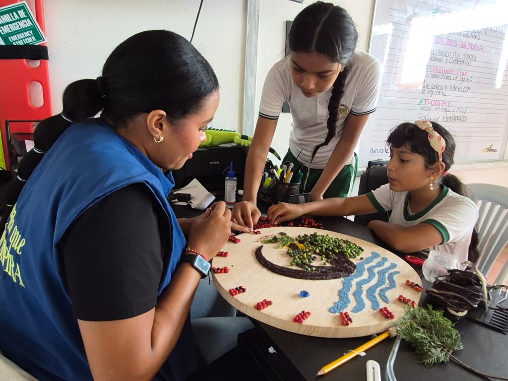 Una niña realiza una actividad manual junto con funcionaria de la Fundación batuta