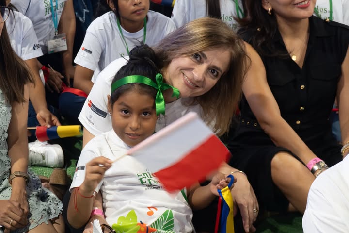 Presidenta de la Fundación Nacional Batuta sonriendo a la cámara con una niña de Perú en brazos